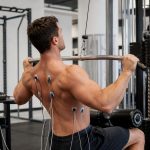 Athlete performing a lat pulldown with EMG electrodes to test back muscle activation