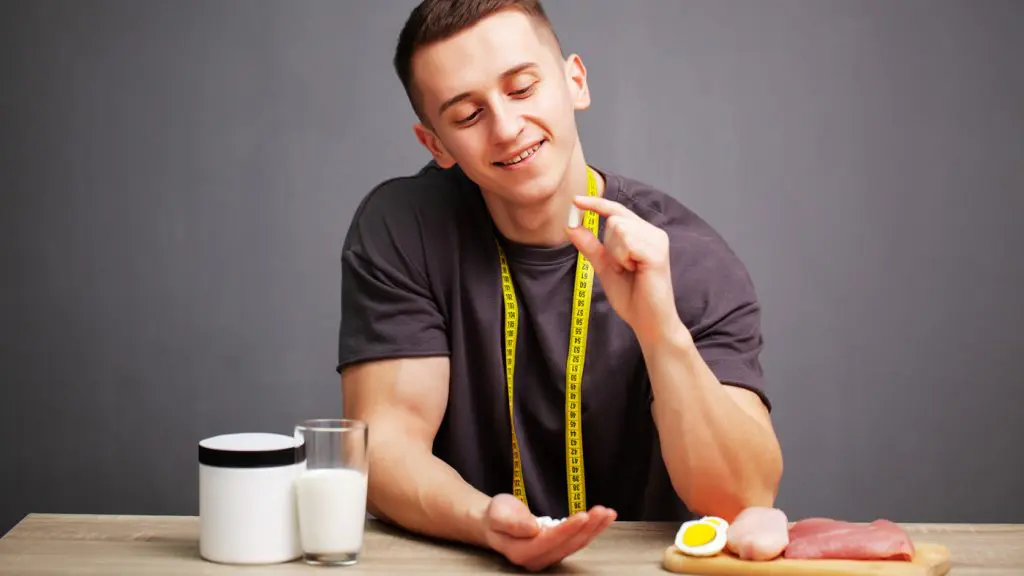 Man holding a supplement capsule beside protein foods and a supplement container