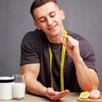 Man holding a supplement capsule beside protein foods and a supplement container