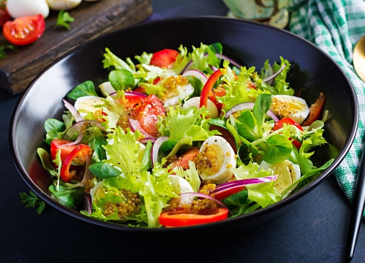 Fresh salad with vegetables tomatoes, red onions, lettuce and quail eggs