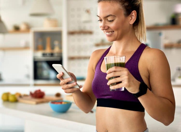 Woman Using Smartphone While Drinking Smoothie