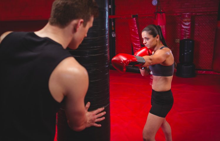 Female Boxer Practicing With Trainer