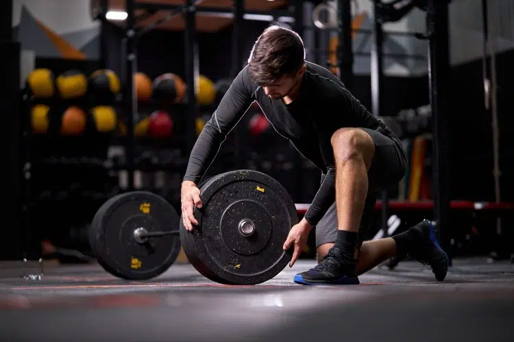 Man Adding Weight Plates On Barbell