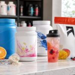 Clear protein powder tubs with fruit drinks on a gym nutrition counter