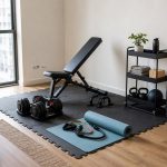 Renter-friendly apartment home gym with removable floor mats, dumbbells, bench, and storage cart