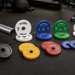 Fractional weight plates with visible printed markings arranged beside an Olympic barbell sleeve
