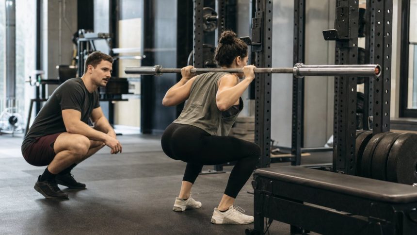 Coach watching a lifter set up for a safe squat with a rack and box nearby