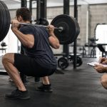 Coach-supervised barbell squat biomechanics session in a modern strength gym