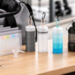 Portable protein powder containers, travel bags, and stackable dispensers beside a shaker bottle