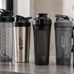 Protein shaker bottles arranged with protein powder and gym accessories for a FitnessVolt review
