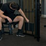 Lifter resting beside a selectorized machine with a hand near the weight stack