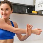 Person stretching indoors beside a kitchen counter