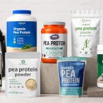 Eight pea protein powder bags arranged with a blender, oats, and berries in a bright fitness kitchen