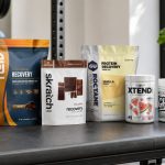 Post-workout recovery drink powders arranged on a bright gym counter