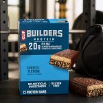 CLIF BUILDERS Cookies N Creme protein bars beside gym equipment