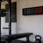 GymNext Flex Timer mounted above a squat rack in a garage gym