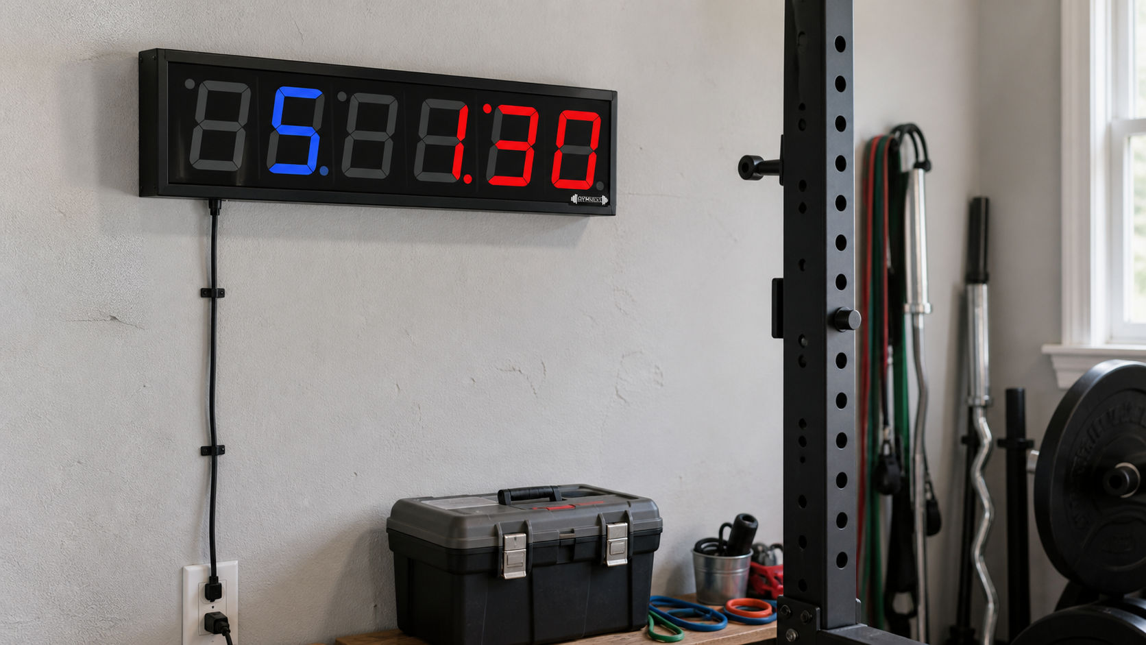 GymNext Flex Timer wall-mounted with its power cord routed to an outlet