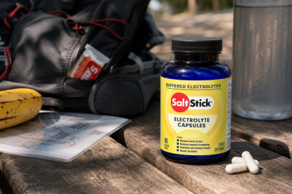Yellow-label SaltStick Electrolyte Capsules beside trail gear, water, and a banana