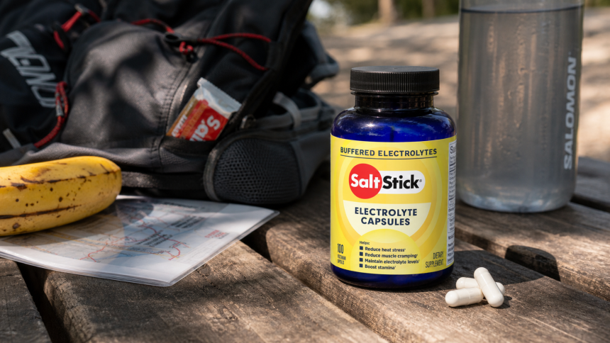 Yellow-label SaltStick Electrolyte Capsules beside trail gear, water, and a banana