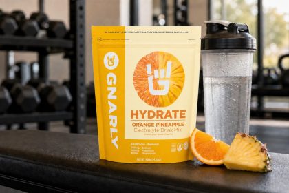 Gnarly Hydrate Orange Pineapple pouch beside a shaker in a gym