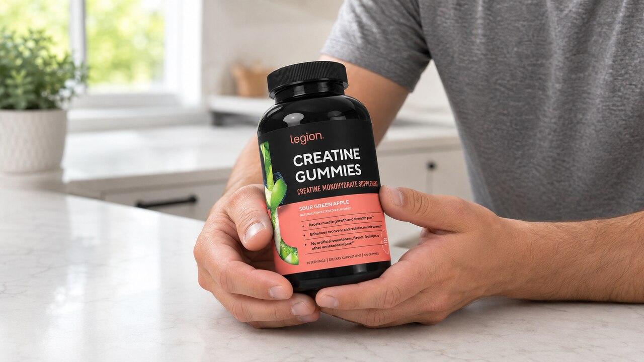 Legion Green Apple creatine gummies bottle held at a table