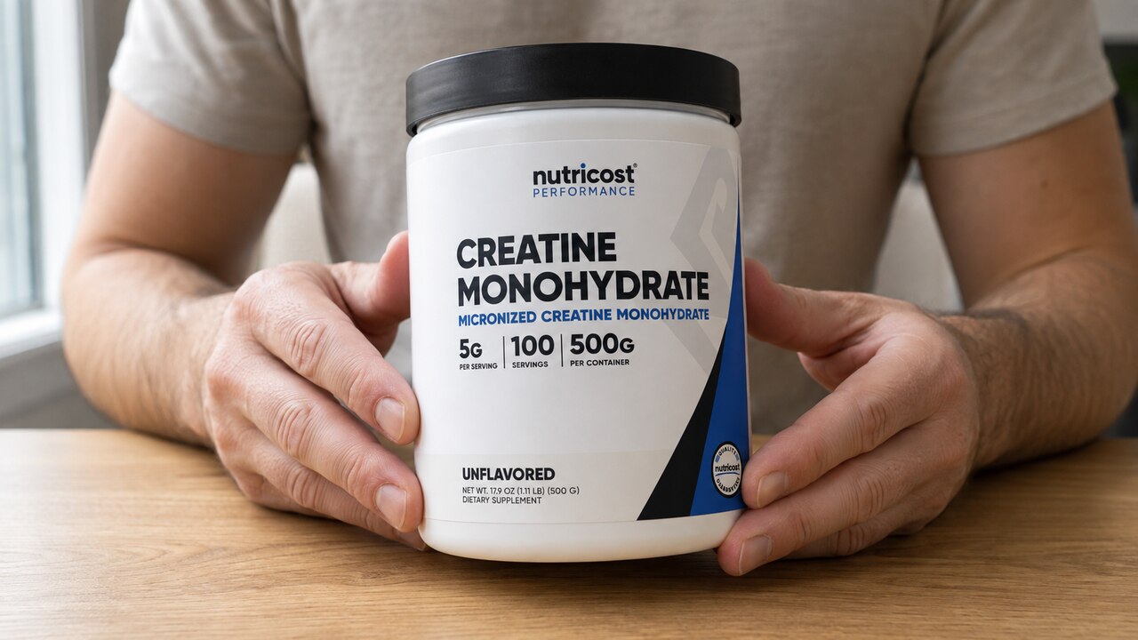 Nutricost 500 g creatine tub held at a table