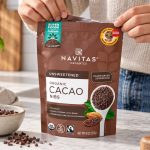 Hands opening a Navitas Organics cacao nibs bag on a kitchen counter