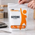 BulkSupplements Glycine Powder 500 g pouch beside a scale and teaspoon