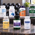 Nine copper supplement bottles arranged on a metal workout bench.