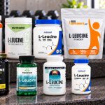 Nine leucine powder and capsule packages arranged on a gym bench with their labels facing forward