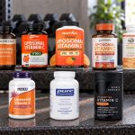 Ten liposomal vitamin C supplement packages arranged on a metal workout bench.