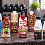 Eight plant-based protein shake products with visible labels on a gym bench
