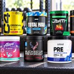 Ten pre-workout tubs arranged on a gym bench with exact flavor labels facing forward
