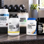 Seven protein powder packages with visible manufacturer labels on a gym bench