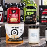 Eight whey-casein protein blend packages arranged on a gym bench with their labels facing forward
